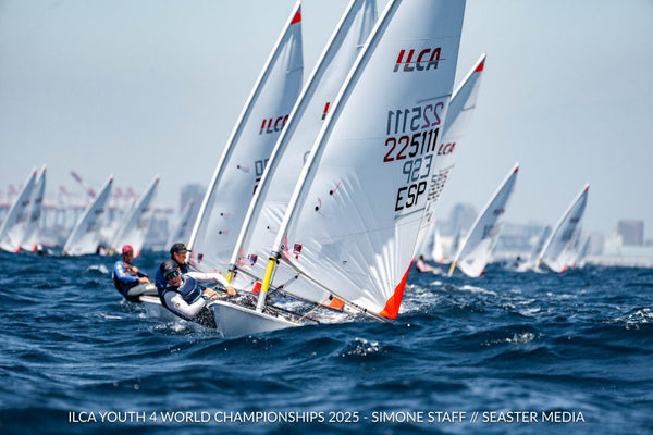 A fleet of ILCA dinghies racing upwind in close quarters